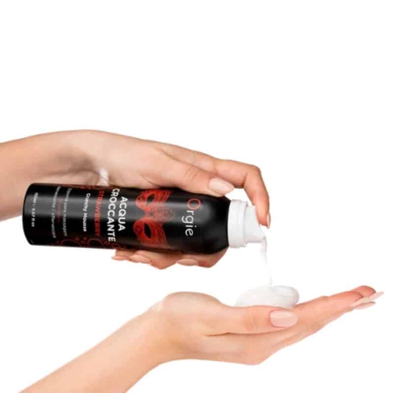 Envase negro de Orgie Acqua Croccante mientras se dispensa mousse blanca sobre una mano