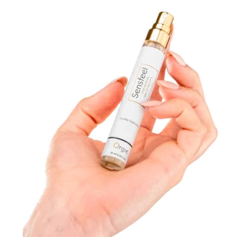 Frasco blanco de perfume Sensfeel de ORGIE con vaporizador dorado, sostenido entre los dedos